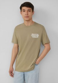 Olijfgroen katoenen t-shirt met korte mouwen, ronde hals en witte grafische tekst op de linkerborst met de tekst "PACIFIC CUSTOMS VENICE BOARDSK8S."