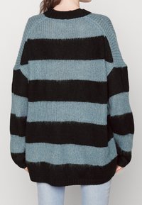 Black and light blue striped oversized sweater with a ribbed texture, round neckline, and drop shoulder design. Soft knit material.