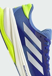 Blue athletic shoe with a textured mesh upper, silver three-stripe design, lime green accents, and a white midsole.