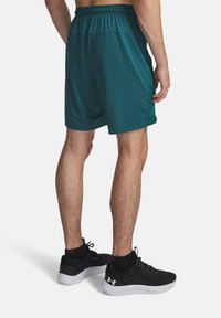 Τιρκουάζ αθλητικά σορτς με πλευρική διχτυωτή επένδυση, ελαστική μέση και λεία υφή. Συνδυάζονται με μαύρα αθλητικά παπούτσια με λευκές σόλες.