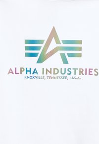 Logo stylisé en "A" avec trois lignes horizontales de chaque côté au-dessus des textes "ALPHA INDUSTRIES" et "KNOXVILLE, TENNESSEE, U.S.A." en couleurs dégradées.