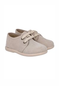 Zapatos de ante beige con punta redonda, cierre de cordones y suela de goma marrón. Diseño simple con acentos mínimos y textura suave.