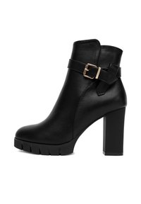 Czarne skórzane botki do kostki z masywnym wysokim obcasem, podeszwą z rowkowanym bieżnikiem oraz dekoracyjnym paskiem z złotą klamrą.
