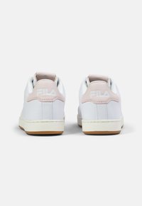 White leather sneakers with a pink accent at the heel, featuring a textured design and a rubber sole with a gum outsole. Fila branding visible.
