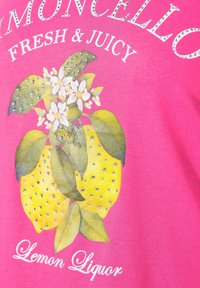 T-shirt rose avec des citrons jaunes, des feuilles vertes, des fleurs blanches et des accents en strass. Le texte indique "Limoncello Frais & Juteux."