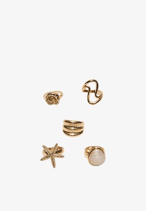 Five gold rings, featuring a spiral, abstract wave, triple band, starfish, and pearl-like stone design on a white background.