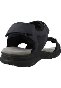 Sandalia negra ajustable con plantilla acolchada, acentos de malla y suela de goma texturizada, que cuenta con correas de velcro dobles para un ajuste seguro.