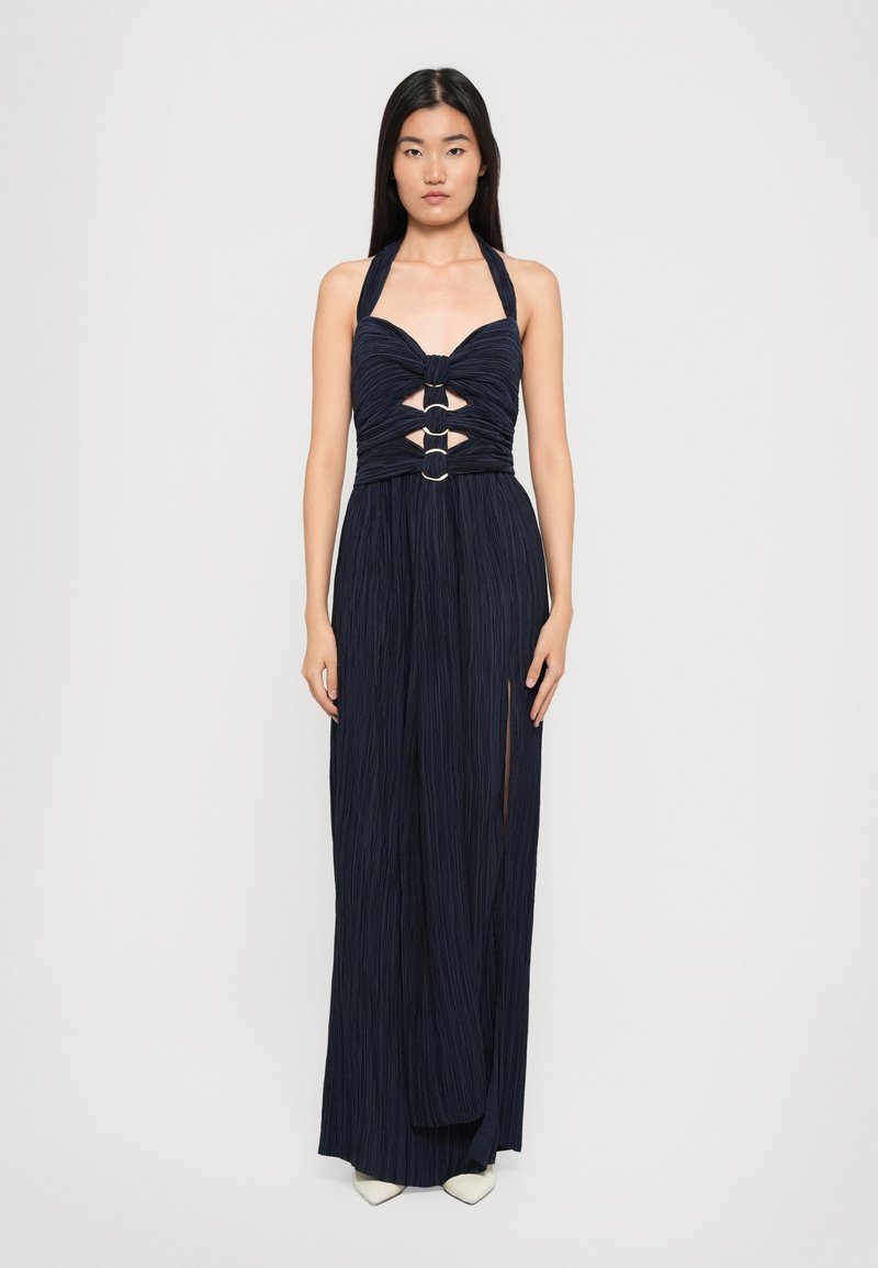 Navy blue halter neck dress with gathered bodice, cut-out front and circular accents, featuring a floor-length design and textured fabric.