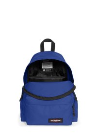 Mochila azul fabricada con tejido duradero, que cuenta con un compartimento principal con cremallera, un bolsillo frontal y un interior negro con detalle de etiqueta.