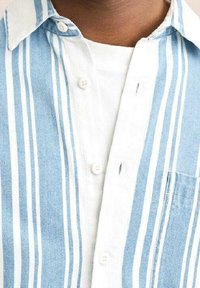 Camisa a rayas azul claro y blanca, diseño con botones, material de algodón, presenta un bolsillo en el pecho y un cuello con textura suave.