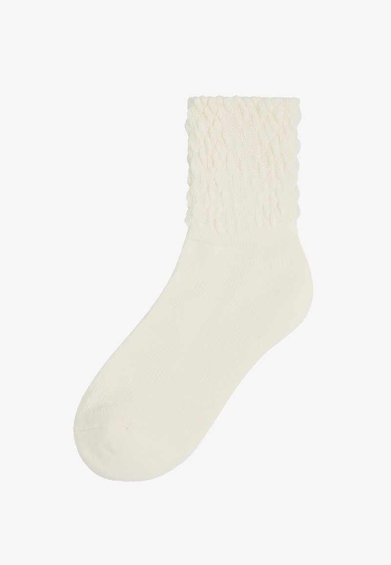 Ein Paar socken in cremefarben mit einem strukturierten, gerippten Muster am Bund und einem glatten Körper, hergestellt aus weichem Stoff.