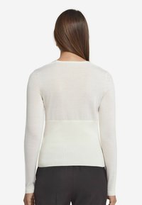 Lätt långärmad tröja i off-white med en något genomskinlig textur, med rundad halsringning och en figurnära silhuett.