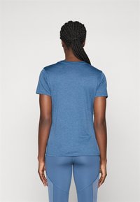 Blå atletisk t-shirt med korta ärmar och rundad halsringning, tillverkad av lätt, texturerad väv. Baksidan har en slät design.