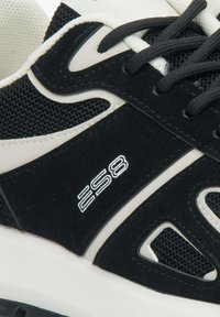Czarno-białe buty sportowe z siateczkowym wierzchem, zamszowymi akcentami, teksturowaną podeszwą i detalem z logo z boku.