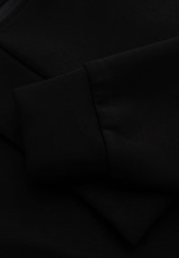 Telado negro que muestra una textura suave y un acabado blando, con un detalle de puño doblado que se destaca en la imagen.