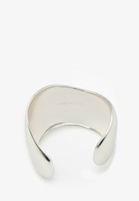Silver cuff bracelet with a smooth, polished surface. Open-ended design featuring rounded edges and subtle branding inside.