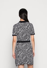 Robe à manches courtes noir et blanc avec un motif léopard, en tissu jersey, et une silhouette cintrée avec une ceinture côtelée noire.