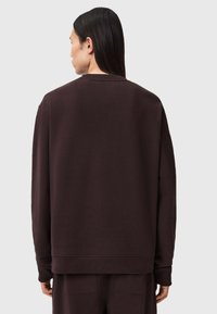 Sweatshirt castanho escuro com decote redondo e mangas longas. Tecido suave e texturizado com um corte descontraído e bainha canelada.