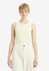 Lichtgele geribde tanktop met een ronde halslijn en zonder mouwen, gecombineerd met crèmekleurige wijde pantalons.