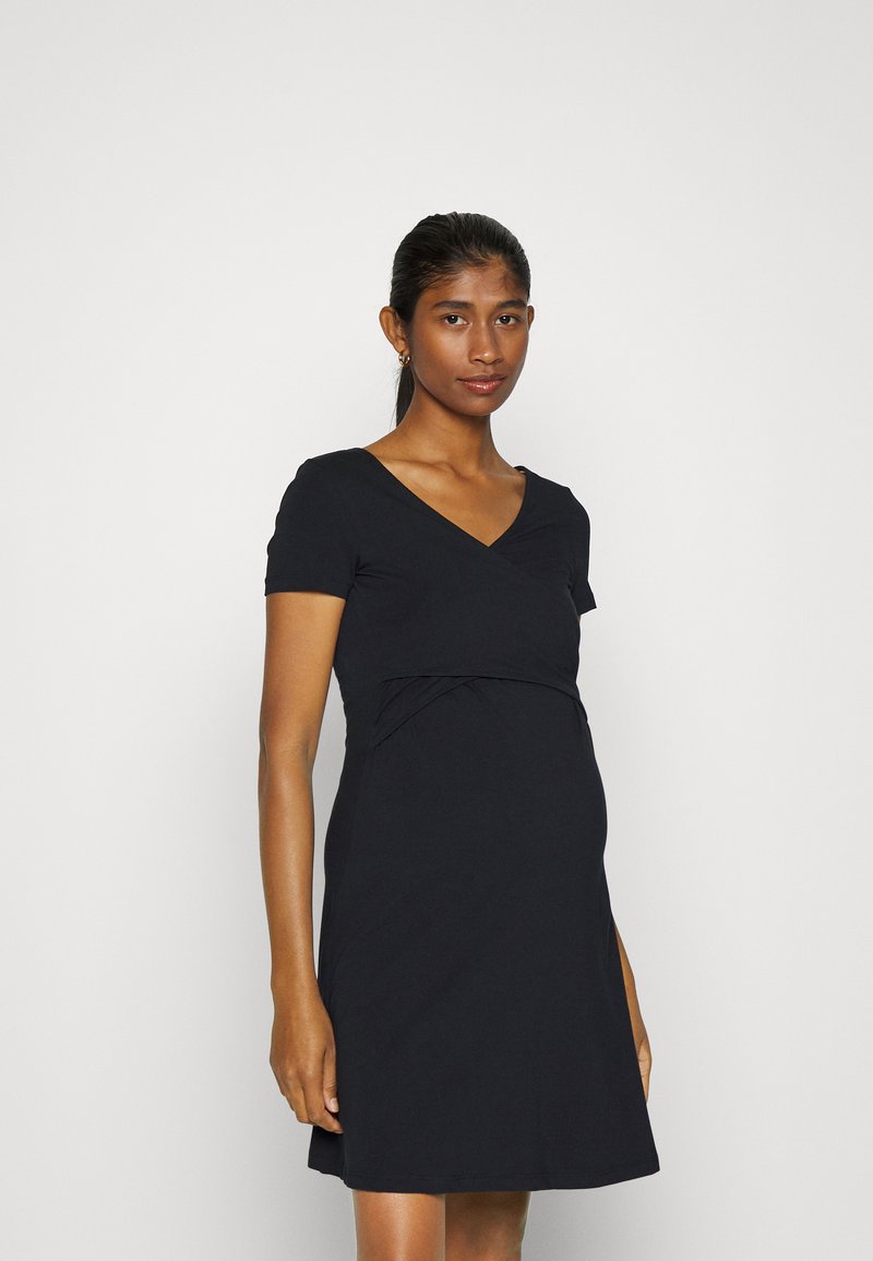 Vestido de maternidade preto feito de tecido suave; possui um decote em V cruzado, mangas curtas e uma cintura franzida para conforto.