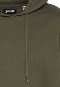 Felpa verde oliva dalla texture a coste, con tasca frontale, cappuccio regolabile con coulisse e un piccolo etichetta del logo vicino al colletto.