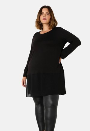 Zwarte lange mouwen top met een gelaagd ontwerp, met een doorzichtige ondersectie en een ronde halslijn, gecombineerd met glanzende zwarte leggings.