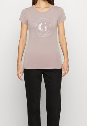 Lichtroze getailleerd T-shirt met korte mouwen, ronde hals en een zilveren cirkelvormig logo met "G" en "ESTABLISHED 1981" gedrukt in het midden.
