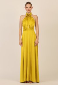 Schulterfreies gelbes Kleid mit Blumenakzent, fließendem Stoff, tailliertem Schnitt und einem bodenlangen Rock. Glatte Textur mit gefalteten Details.