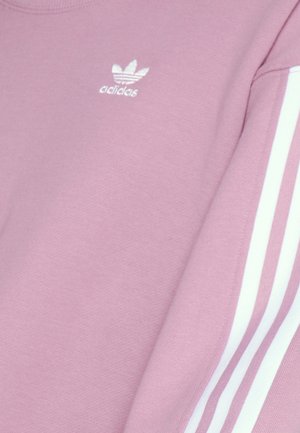 Sudadera rosa con diseño de tres rayas blancas en las mangas, que presenta un logo bordado de Adidas en el frente. Tejido suave y texturizado.