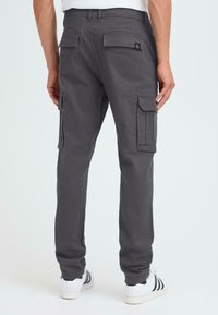 Grå cargos med avslappet passform, med sidelommer og baklommer, samt logo-patch bak. Stoffet har en jevn tekstur.
