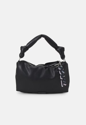 Sac à main en cuir noir souple avec poignée torsadée, fermeture éclair et un pendentif décoratif avec le logo KARL suspendu sur le côté.