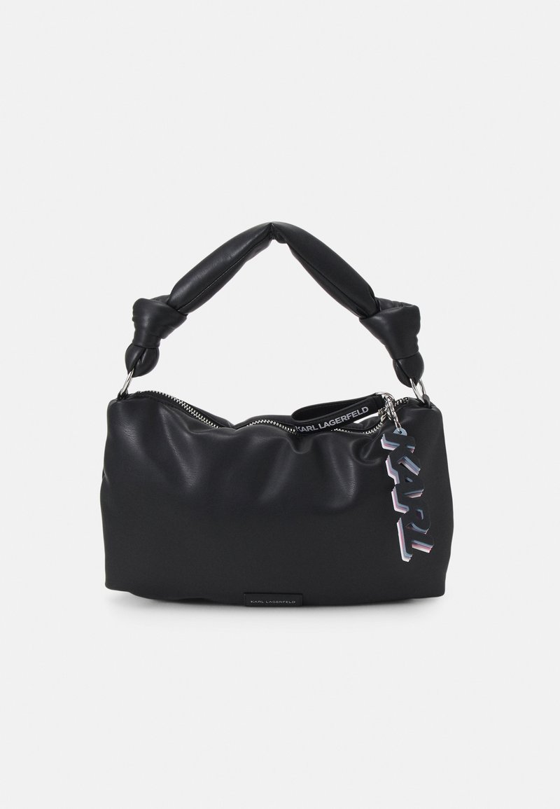 Sac à main en cuir noir souple avec poignée torsadée, fermeture éclair et un pendentif décoratif avec le logo KARL suspendu sur le côté.