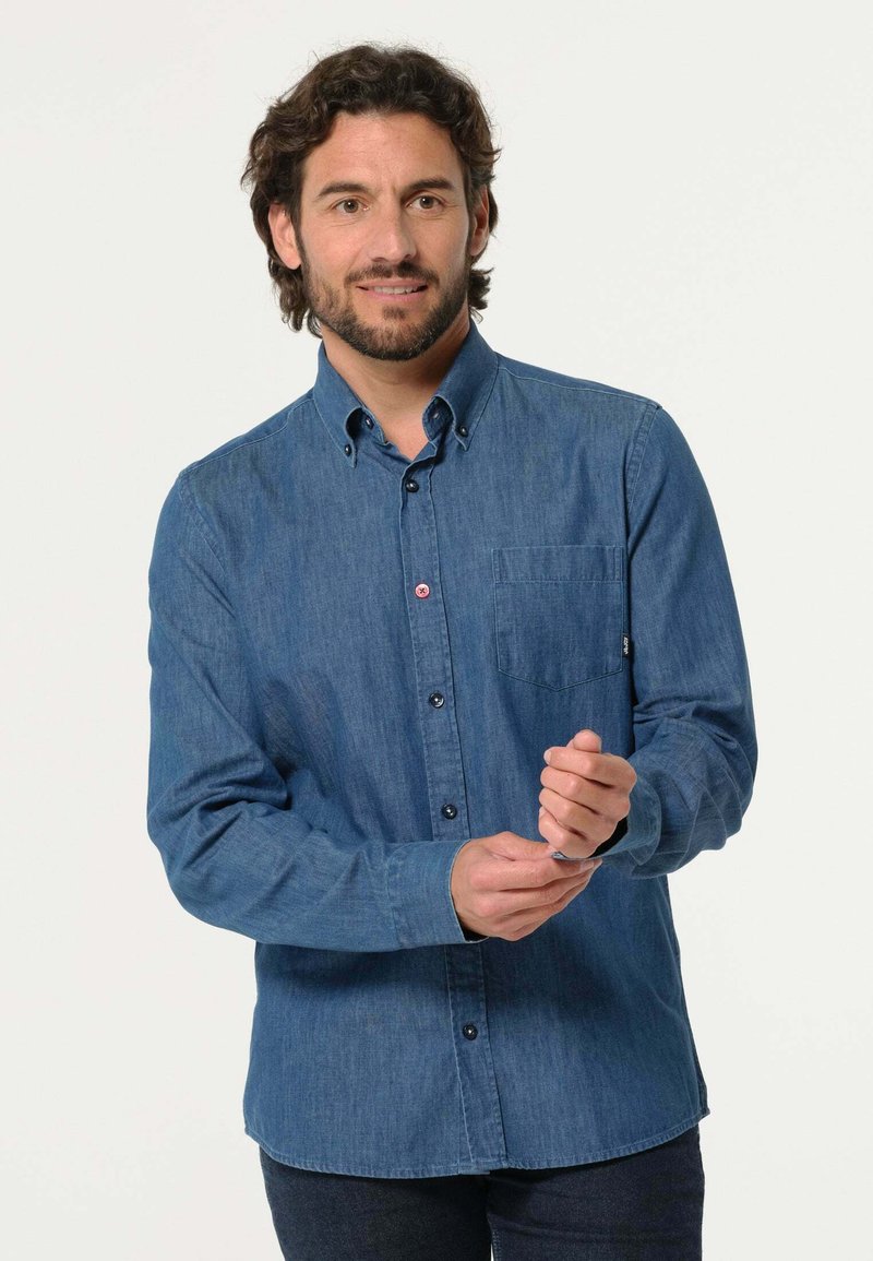 Donkerblauw denim overhemd met lange mouwen, een button-down kraag, een enkele borstzak en een knoopsluiting aan de voorkant. Heeft een subtiele textuur.