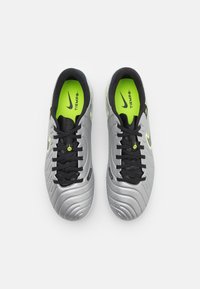 Silver soccer cleats with a textured surface, black laces, and a neon green inner lining featuring a logo on the tongue.