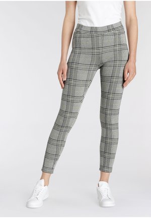 Gray plaid leggings with black and yellow accents, featuring a fitted design and elastic waistband. Paired with white sneakers.