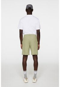 Spodenki w jasnym oliwkowym kolorze, w luźnym kroju, z elastycznym pasem i bocznymi kieszeniami. W komplecie z białą koszulką i szarym czapką.
