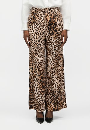 Παντελόνια με φαρδιά μπατζάκια σε καφέ και μαύρο λεοπάρ σχέδιο, φορεμένα με λευκό πουκάμισο και μαύρες μυτερές γόβες, εμπρόσθια όψη από τη μέση και κάτω.