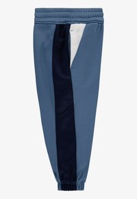 Blå atletisk jogger med en marineblå sideliste, elastisk talje og en sidelomme. Fremstillet af fugttransporterende stof med en glat tekstur.