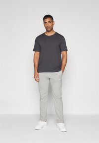 Herreoutfit bestående af en mørkegrå kortærmet t-shirt og lysegrå sweatpants, suppleret af hvide sneakers.