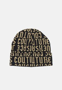 Črna pletena kapa z drznim zlatim napisom "COUTURE" v različnih usmeritvah, z zavihanjem na robu. Mehka tekstura.