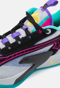 Sportsko med en grå stofoverdel, sorte accenter, livlige pink og turkise detaljer, tekstureret overflade og en gummisål.