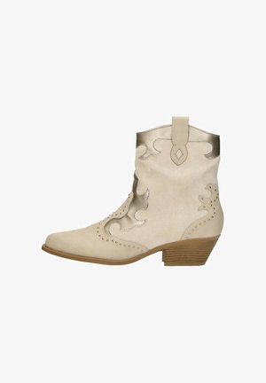 Beige suède enkellaarzen met metallic accenten, decoratieve stiksels, ronde neus en een lage houten hak.
