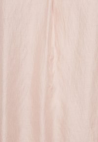 Tissu rose doux avec une texture verticale subtile, la lumière naturelle créant des ombres et des reflets délicats.