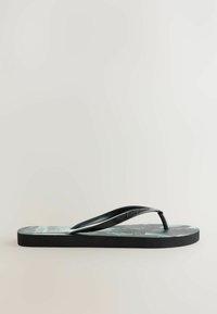 Sort flip-flop med struktureret strop, mønstret fodseng i grønne nuancer, og en flad sort sål. Simpelt design med sideprofilvisning.