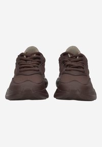 Brown athletic shoes with textured mesh material, featuring lace-up closure, padded collar, and a rubber outsole.
