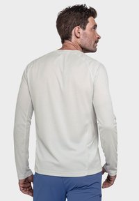 Langärmliges, hellgraues Sportshirt mit strukturiertem Muster, Rundhalsausschnitt und taillierter Passform. Verfügt über Raglanärmel und eine glatte Oberfläche.