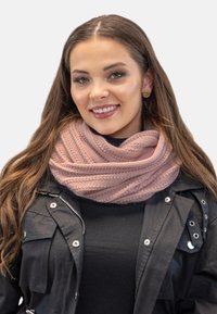 Écharpe infinie rose tricotée avec un relief texturé, enroulée élégamment autour du cou, associée à une veste et un haut noirs.