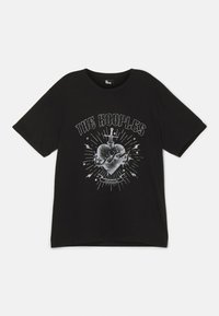 Camiseta de algodón negra con un diseño gráfico que incluye un corazón, una espada y rayos en blanco. Corte relajado con mangas cortas.