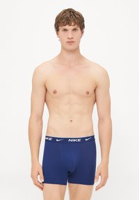 Tengerészkék, fehér Nike logóval ellátott boxer alsó, sima, rugalmas anyaggal és testhez álló kialakítással.