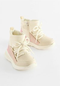 Stivaletti beige per bambini con dettagli rosa, caratterizzati da punte arrotondate, lacci bianchi e una cerniera laterale per una facile vestibilità. Suole testurizzate per una buona aderenza.